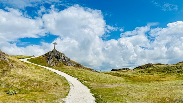 A winding path leading toward a cross on a distant hill