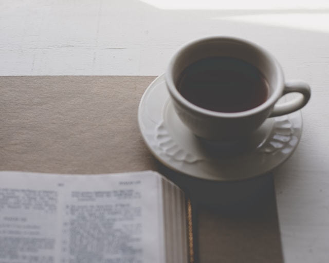 Quiet devotional scene with coffee and an open Bible, suggesting prayer, watchfulness, and thanksgiving.